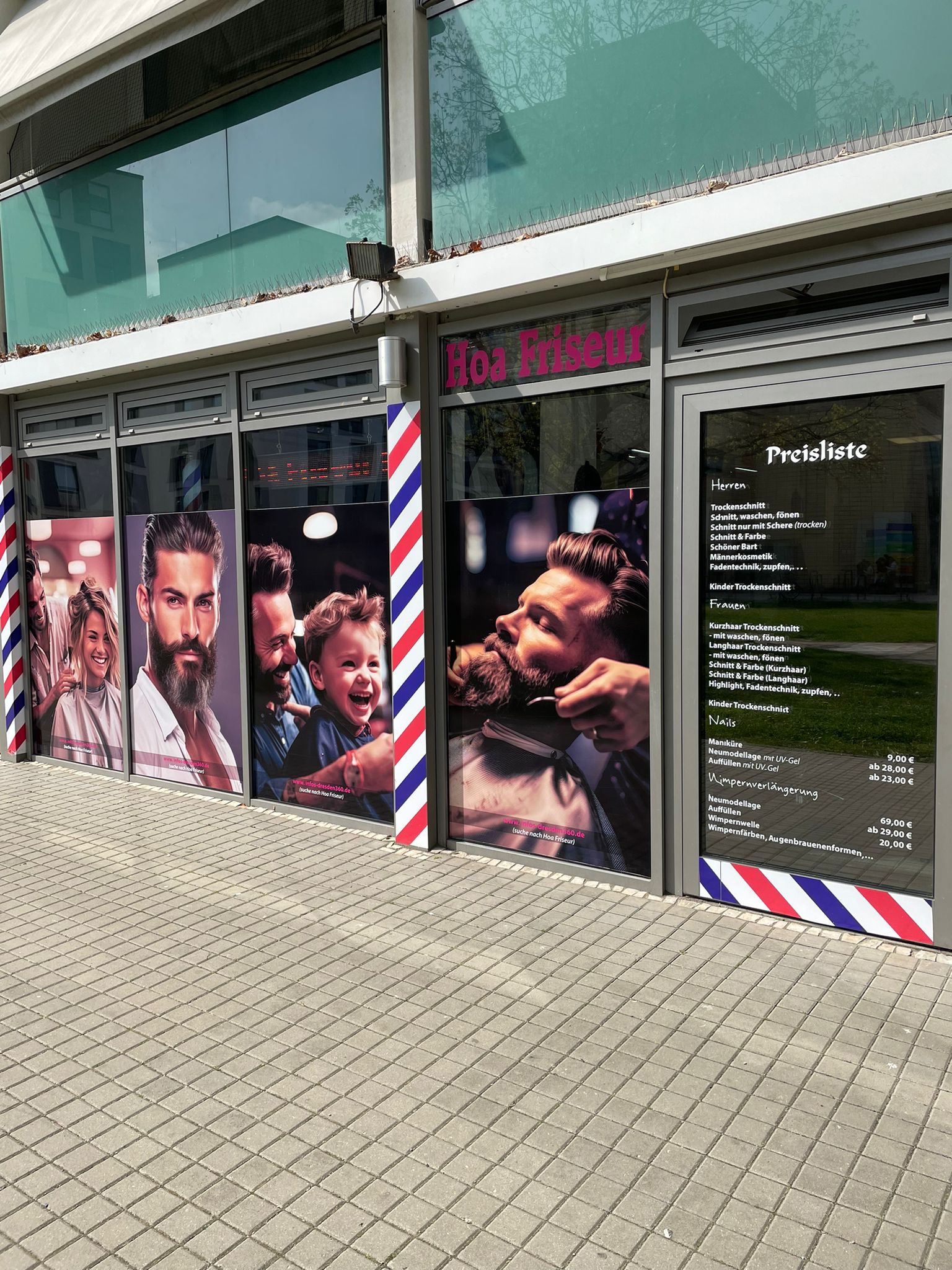 Friseursalon mit Bildern von lächelnden Menschen und stilvollen Haarschnitten an der Außenfront.