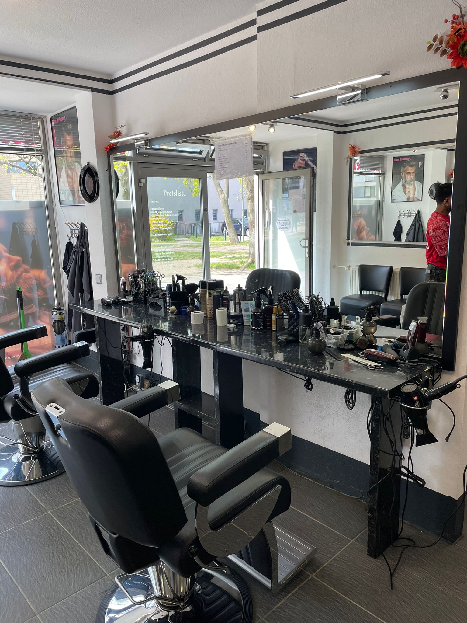 Friseurgeschäft mit zwei Friseurstühlen, Spiegeln und Friseurutensilien in moderner Einrichtung.