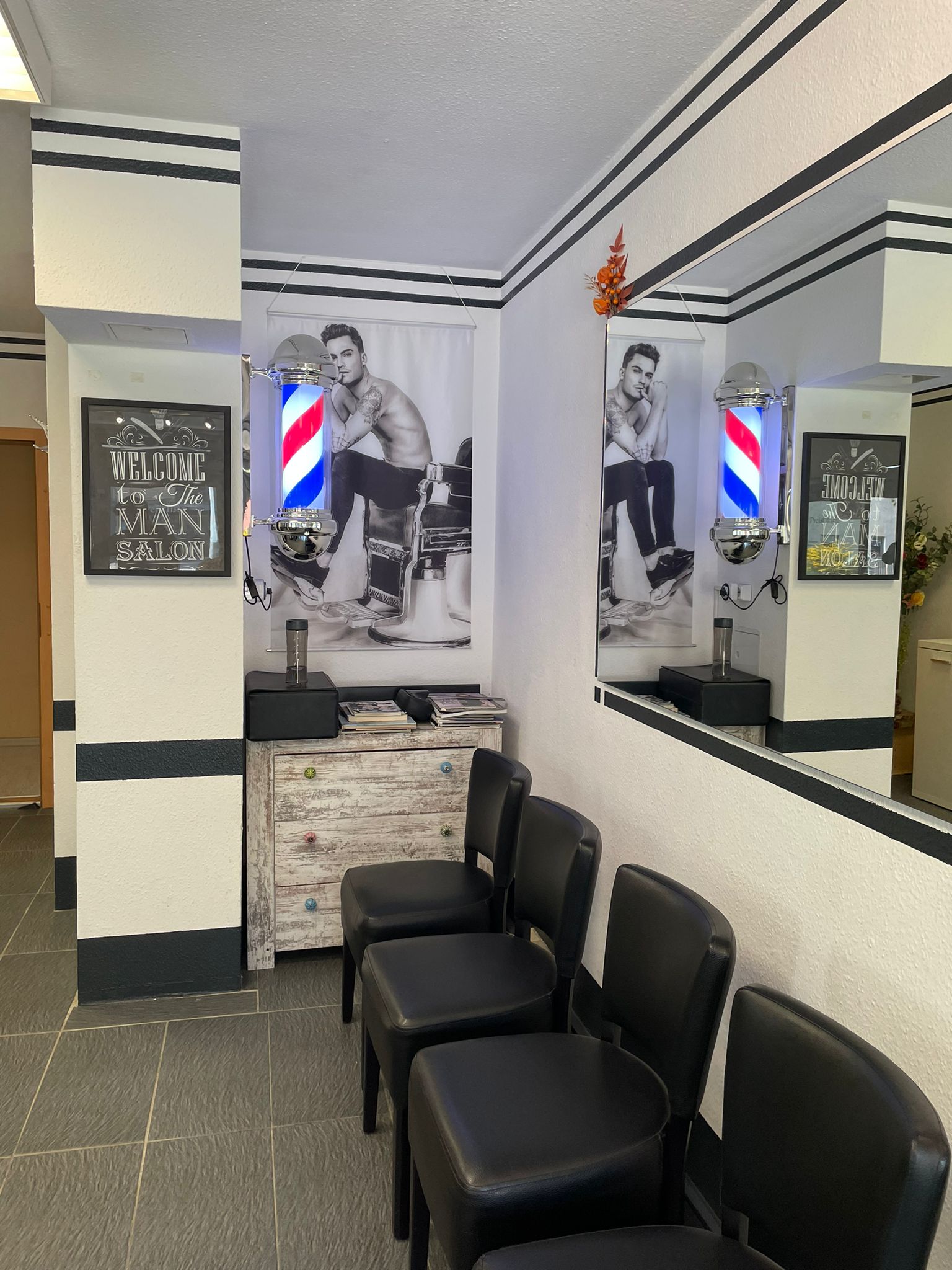 Friseursalon, schwarz-weiße Deko, männliches Modell auf Poster, Barbershopstange spiegelnd.
