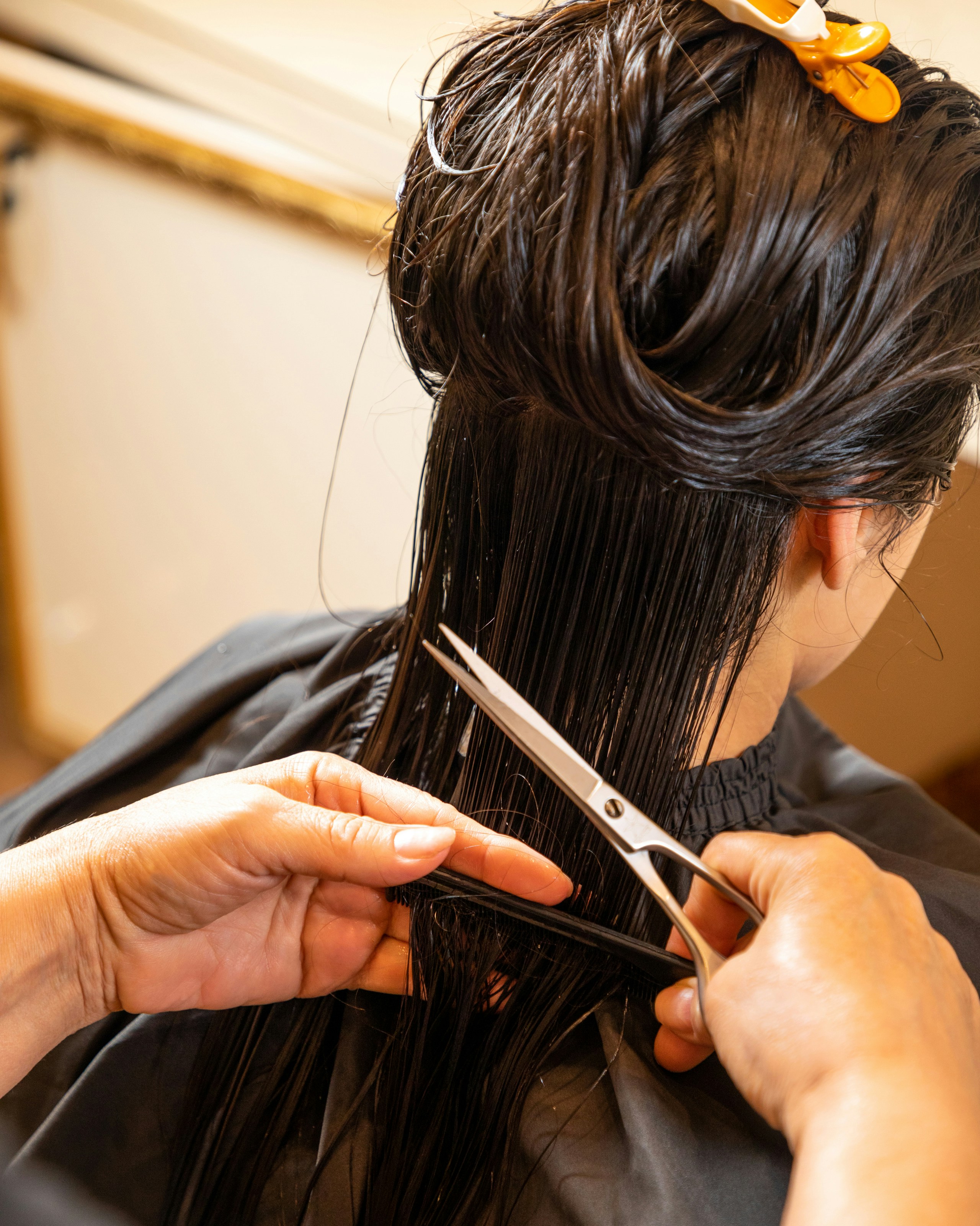 Eine Person erhält einen Haarschnitt, nasses dunkles Haar, Friseur mit Schere fokussiert.