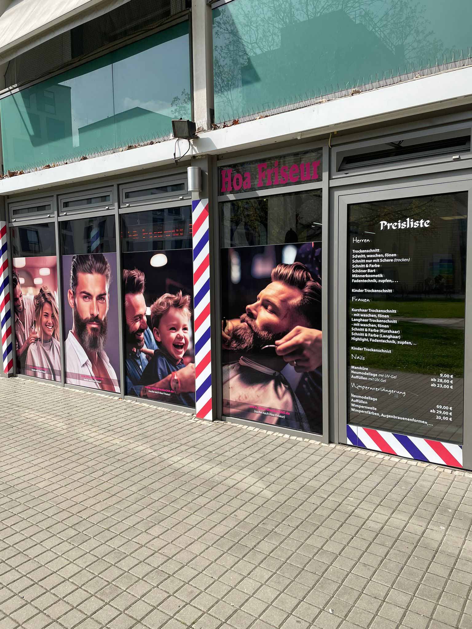 Barbershop mit lebhaften Fenstergrafiken von lächelnden Personen beim Haareschneiden.