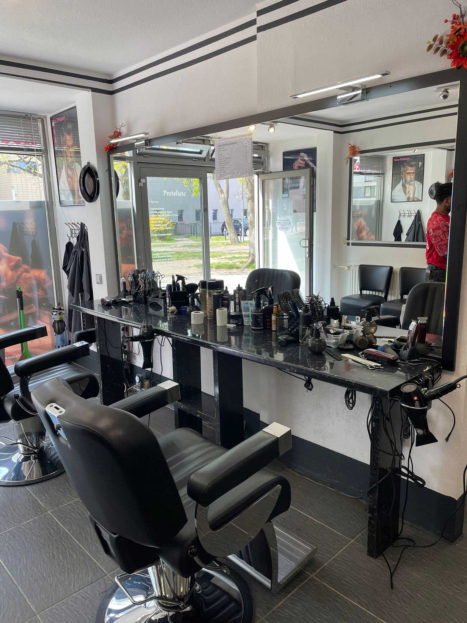 Ein leerer Friseursalon mit zwei schwarzen Stühlen und vielen Stylingprodukten.